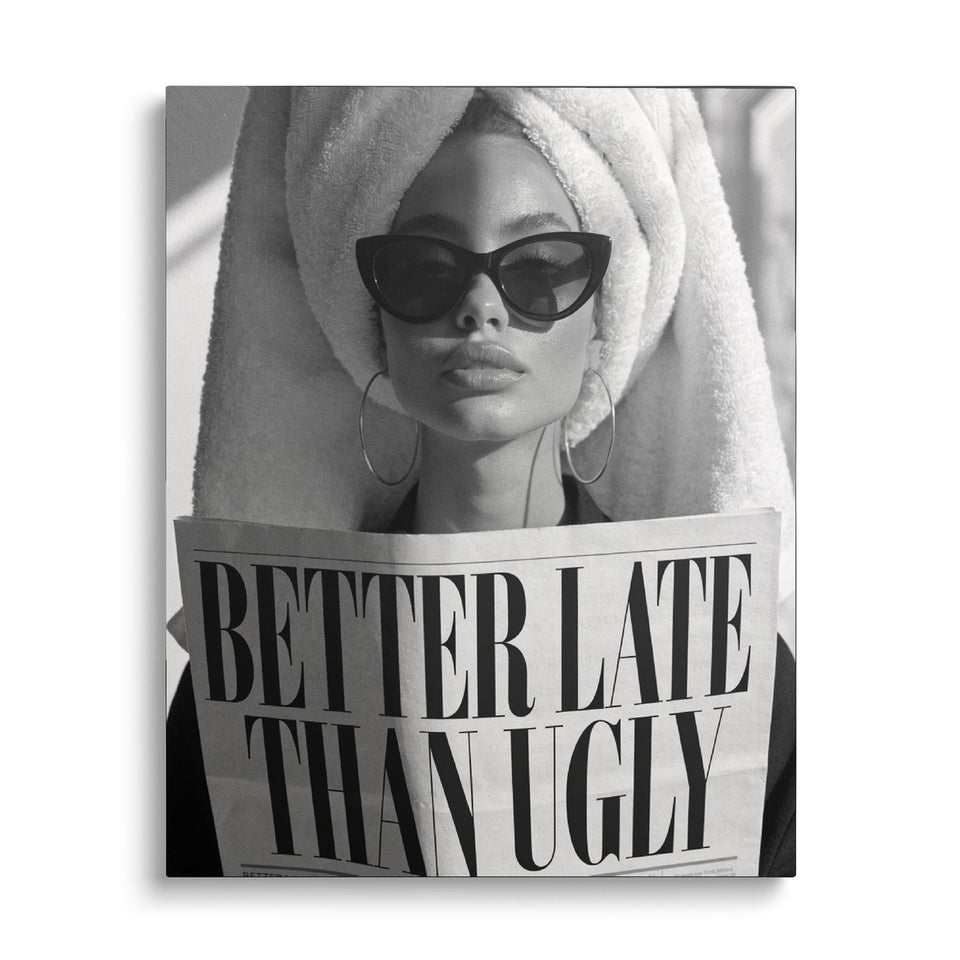 Toile Better Late Than Ugly vue de face sur fond blanc : photographie noir et blanc d’une femme en turban de serviette et lunettes noires lisant un journal titré « Better late than ugly »