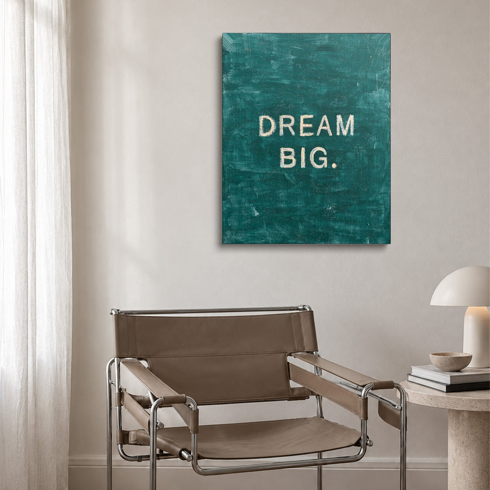 Toile Dream Big accrochée au-dessus d’un fauteuil en cuir et acier