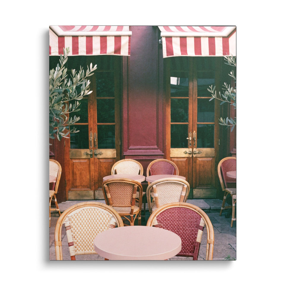 Toile En Terrasse vue de face sur fond blanc : photographie d’une terrasse de café parisien, chaises en rotin et stores à rayures rouges