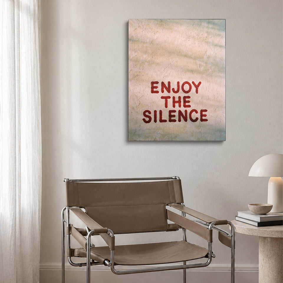 Toile Enjoy the Silence accrochée au-dessus d’un fauteuil en cuir et acier