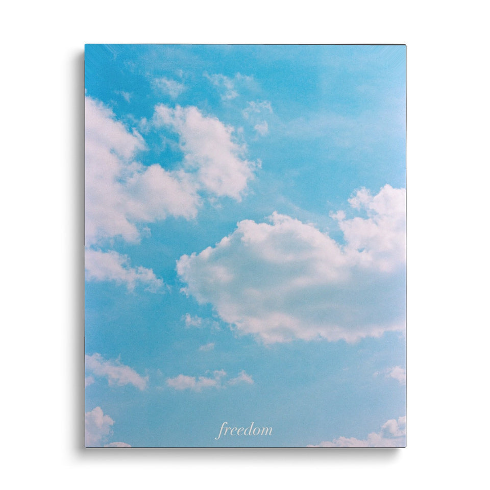 Toile Freedom vue de face sur fond blanc : photographie d’un ciel bleu semé de nuages blancs, avec le mot « freedom » en petites lettres