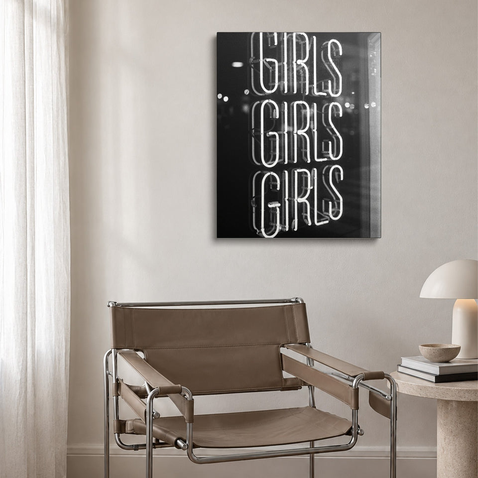 Toile Girls Girls Girls accrochée au-dessus d’un fauteuil en cuir et acier