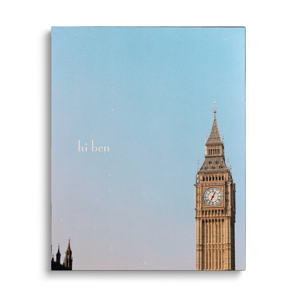 Toile Hi Ben vue de face sur fond blanc : photographie de la tour de l’horloge de Londres dans le coin d’un grand ciel bleu, avec les mots « hi ben »