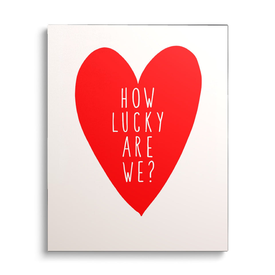 Toile How Lucky Are We vue de face sur fond blanc : grand cœur rouge portant la question « How lucky are we? » en fines lettres blanches, sur fond crème