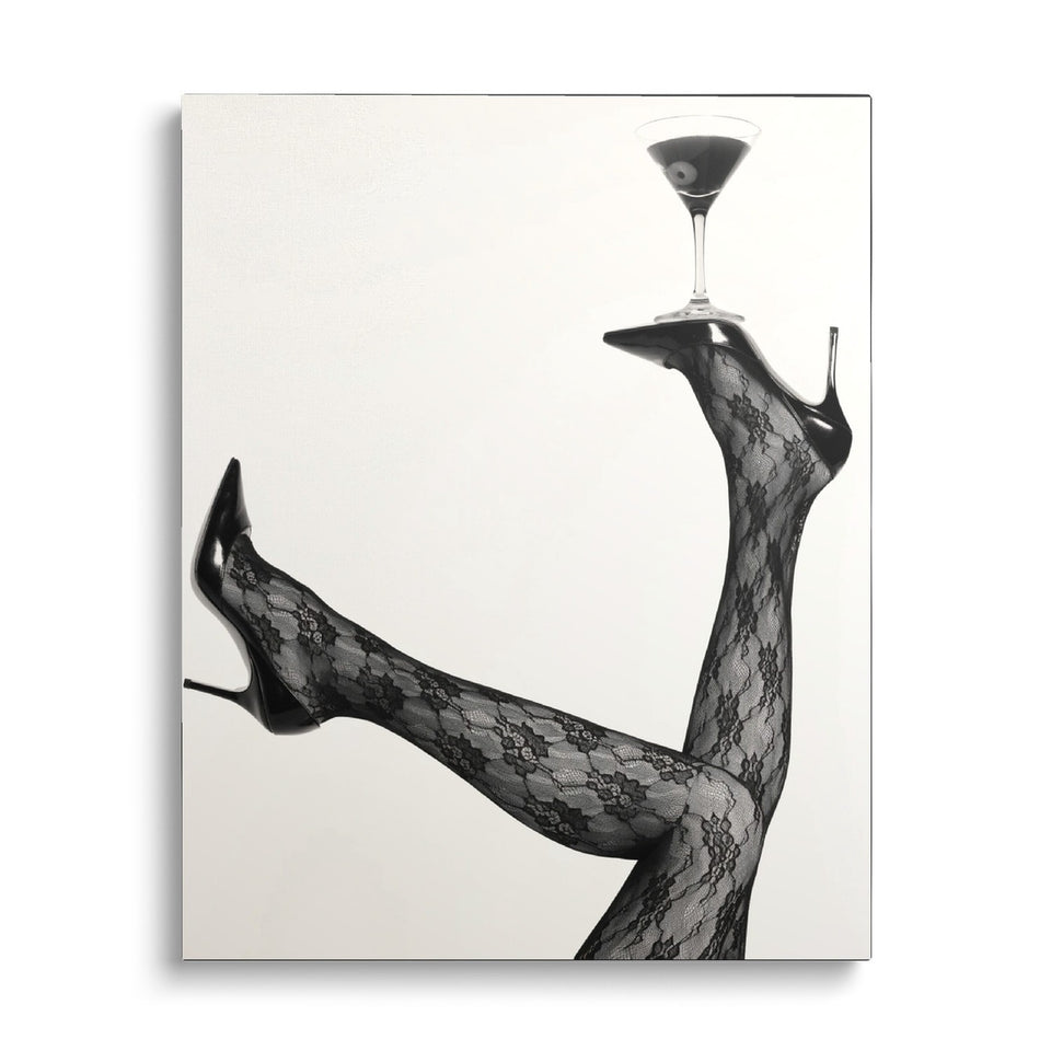 Toile L’Équilibriste vue de face sur fond blanc : photographie noir et blanc de jambes en collants de dentelle et escarpins, un verre à cocktail en équilibre sur une semelle