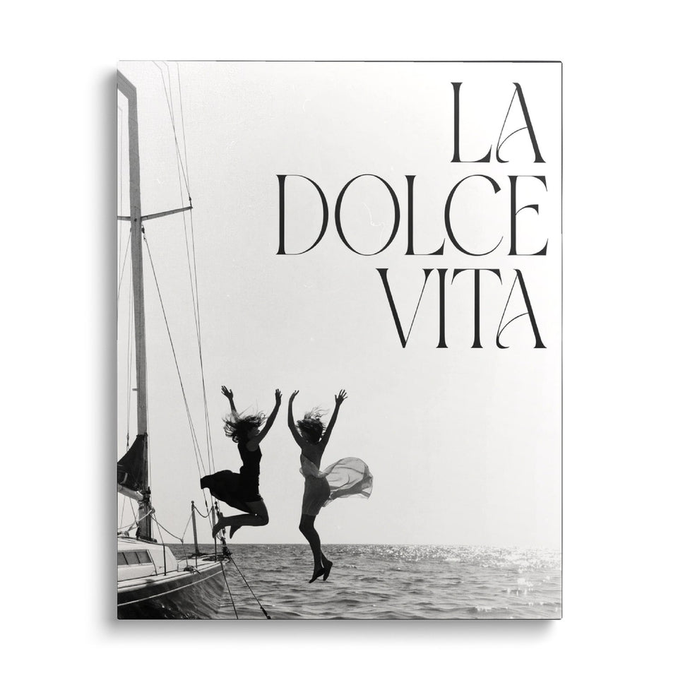 Toile Le Grand Saut vue de face sur fond blanc : photographie noir et blanc de deux femmes sautant d’un voilier dans la mer, avec l’inscription « La dolce vita »
