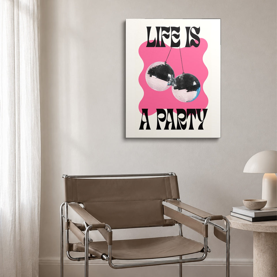 Toile Life Is a Party accrochée au-dessus d’un fauteuil en cuir et acier