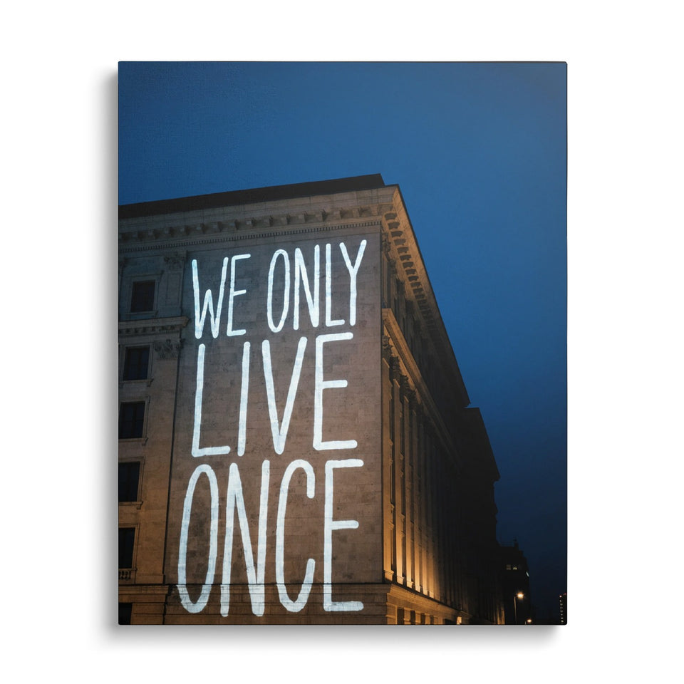 Toile Live Once vue de face sur fond blanc : photographie de nuit d’un immeuble de pierre sur lequel s’inscrit en grandes lettres lumineuses « We only live once »