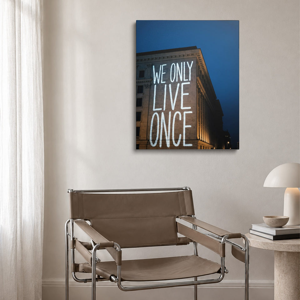 Toile Live Once accrochée au-dessus d’un fauteuil en cuir et acier