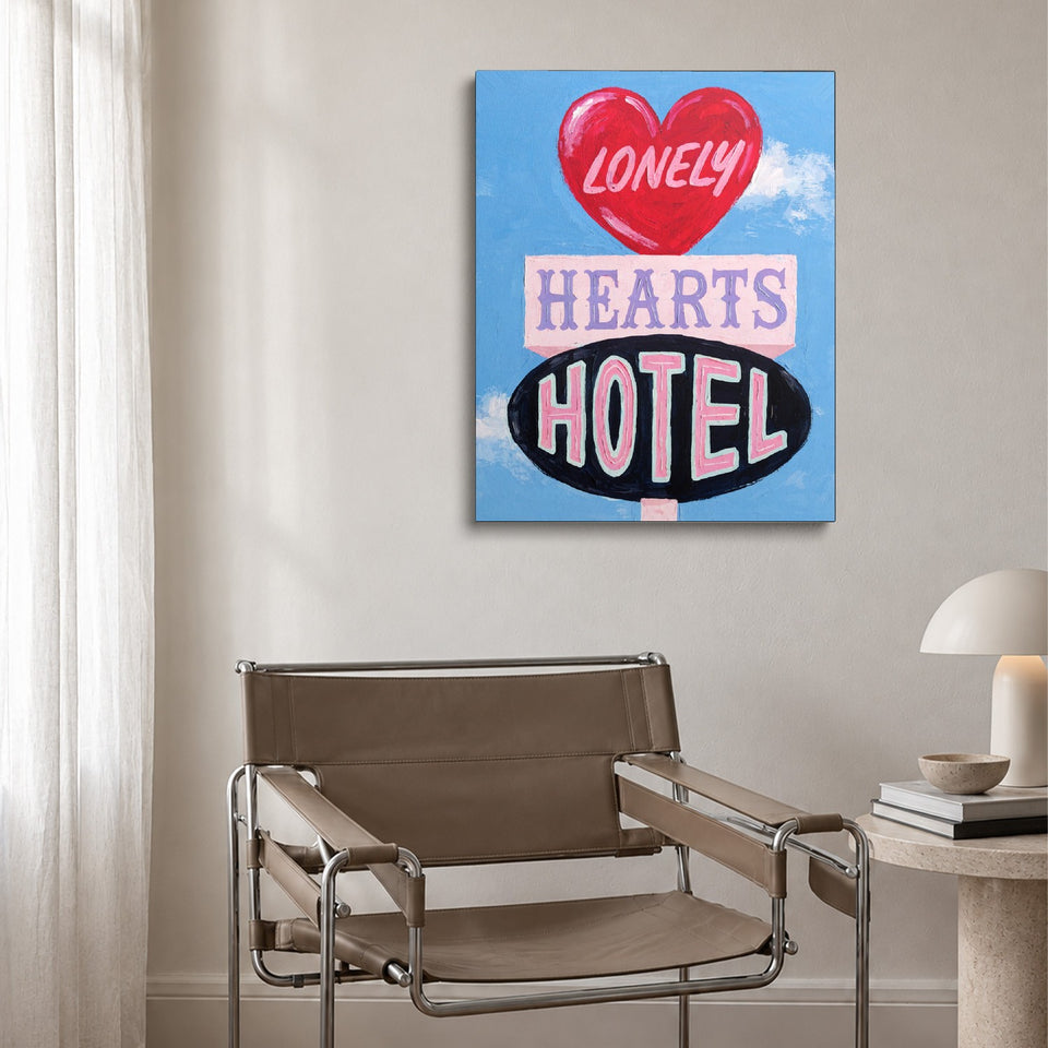 Toile Lonely Hearts Hotel accrochée au-dessus d’un fauteuil en cuir et acier