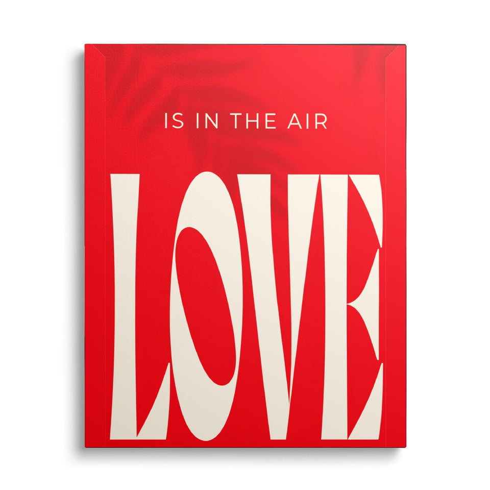 Toile Love Is in the Air vue de face sur fond blanc : mot « Love » en immenses lettres crème étirées sur fond rouge vif, surmonté de « Is in the air »