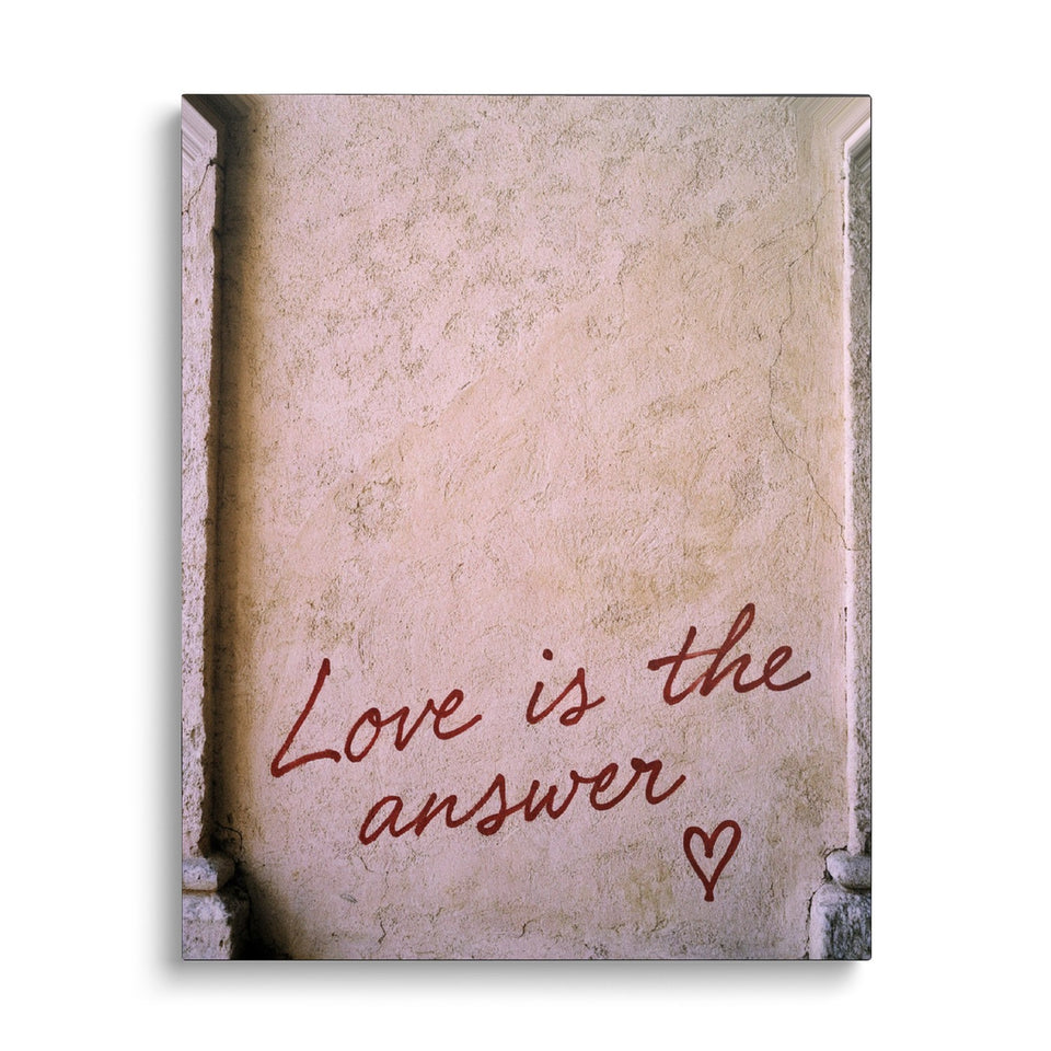 Toile Love Is the Answer vue de face sur fond blanc : inscription « Love is the answer » en écriture rouge suivie d’un cœur, sur un mur d’enduit clair