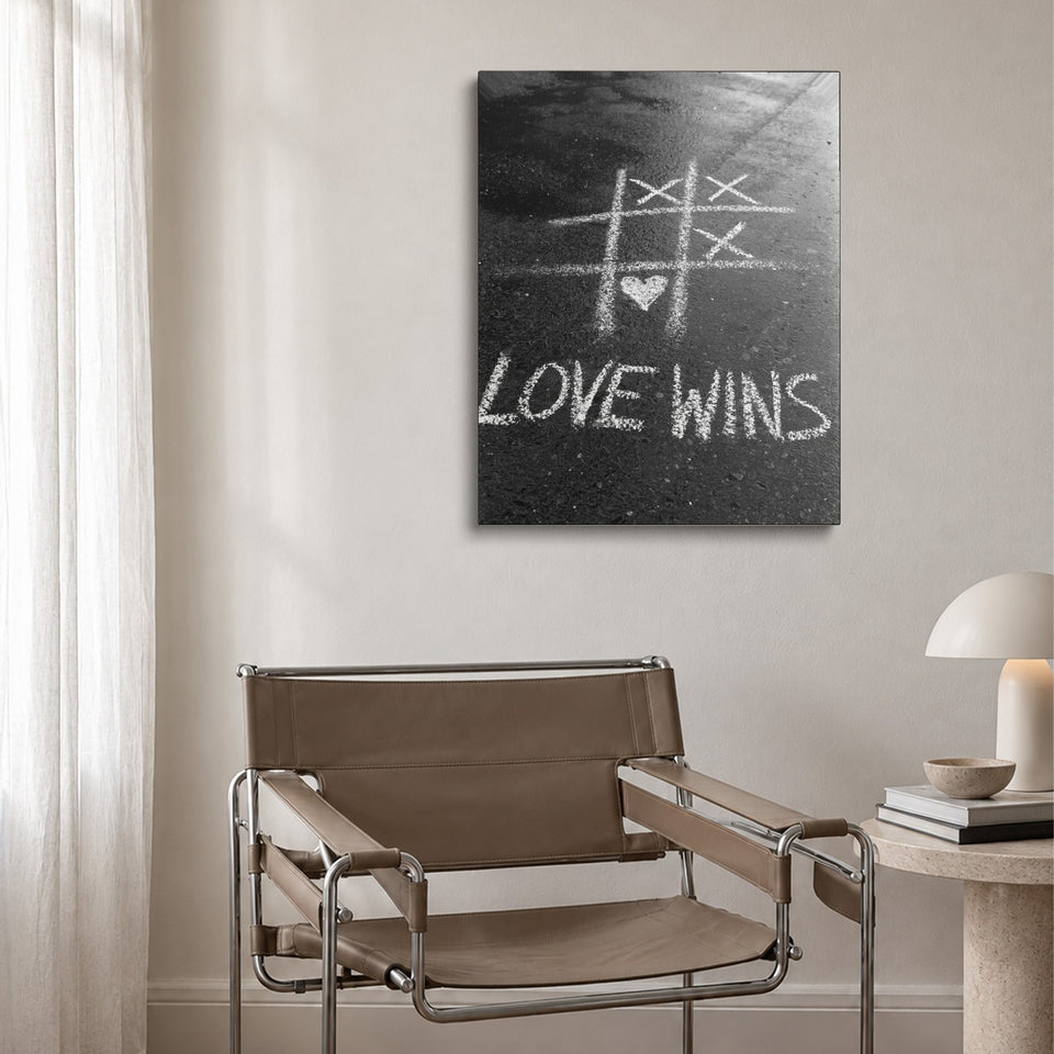 Toile Love Wins accrochée au-dessus d’un fauteuil en cuir et acier