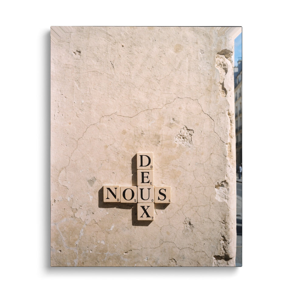Toile Nous Deux vue de face sur fond blanc : photographie de lettres de jeu en bois formant les mots « Nous » et « Deux » croisés, collées sur un mur de pierre