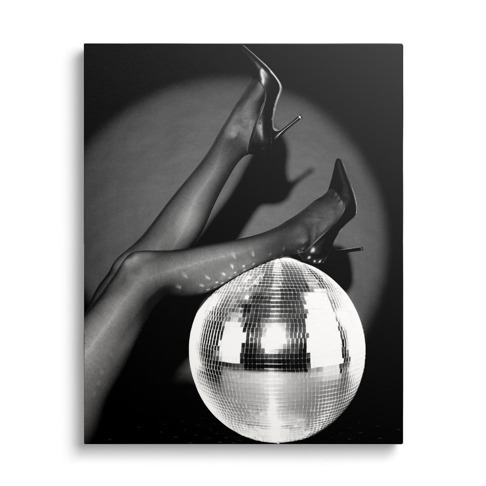 Toile Nuit Blanche vue de face sur fond blanc : photographie noir et blanc de jambes en collants et escarpins posées sur une grande boule à facettes