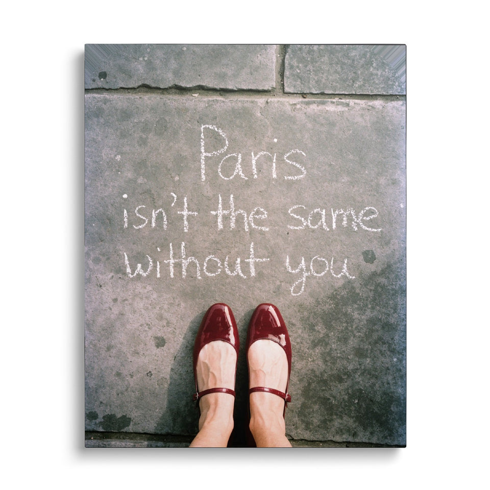 Toile Paris Sans Toi vue de face sur fond blanc : photographie vue du dessus de babies vernies rouges devant l’inscription à la craie « Paris isn’t the same without you »