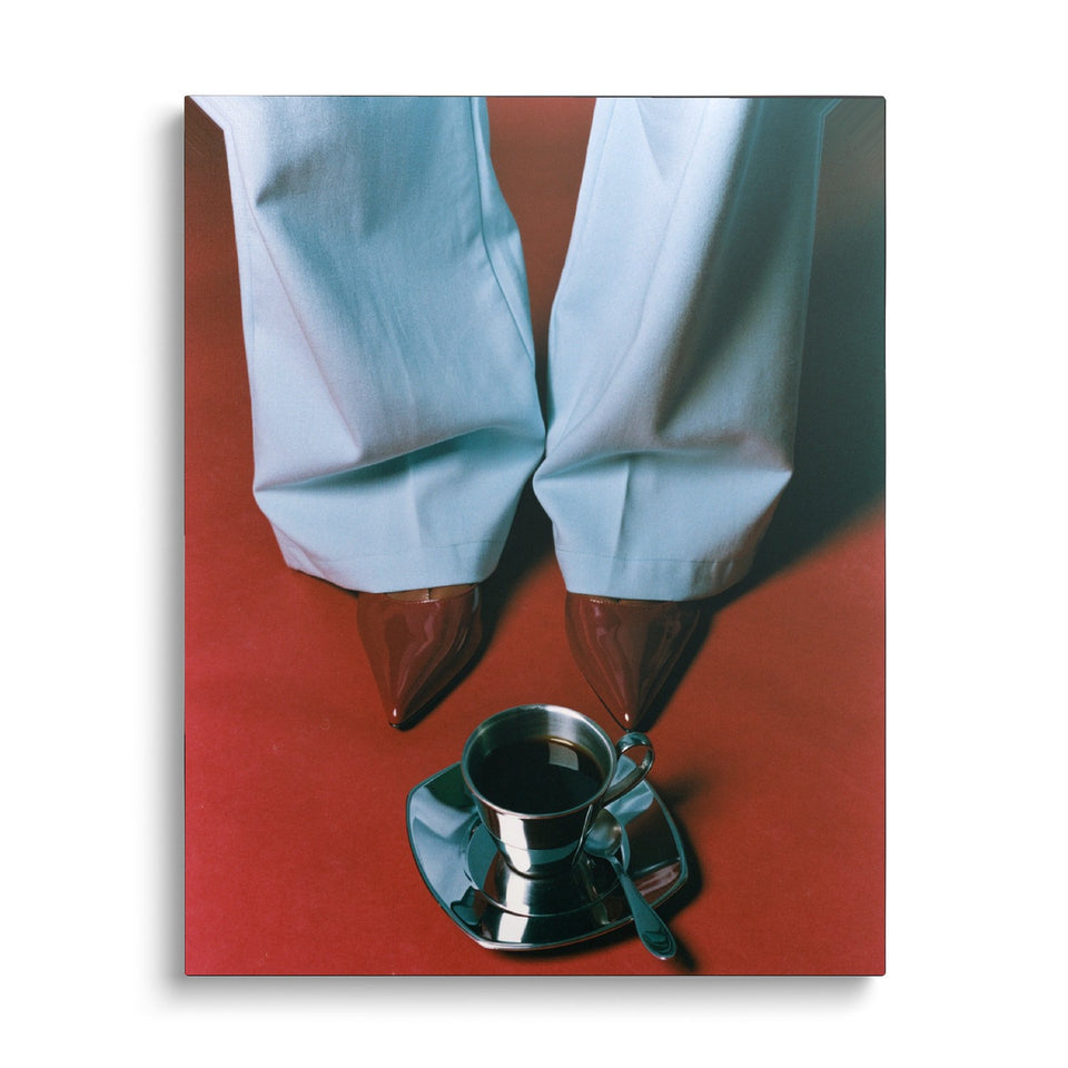 Toile Rouge Café vue de face sur fond blanc : photographie vue du dessus d’un pantalon bleu ciel et de souliers bordeaux sur un sol rouge, une tasse de café entre les pieds