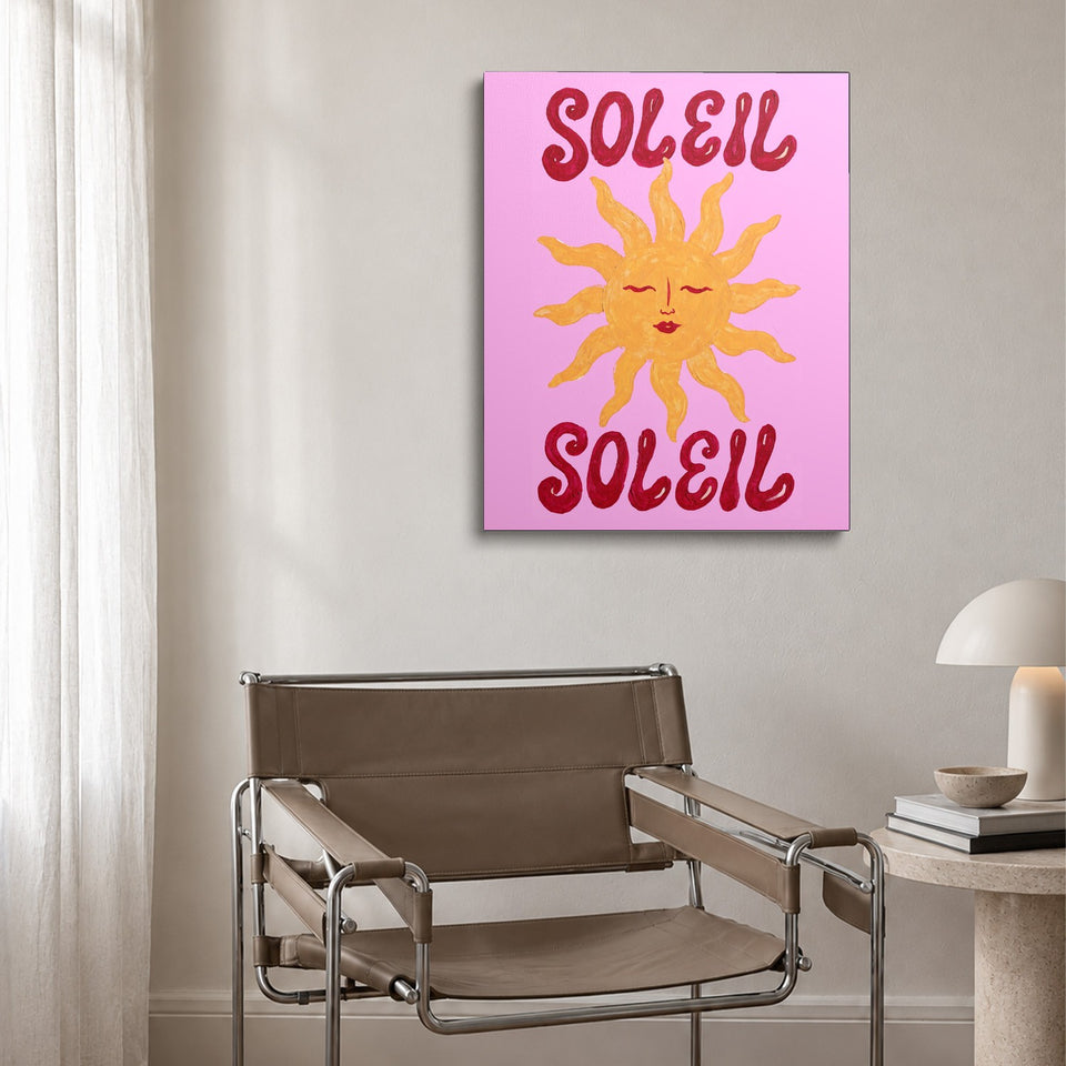 Toile Soleil Soleil accrochée au-dessus d’un fauteuil en cuir et acier