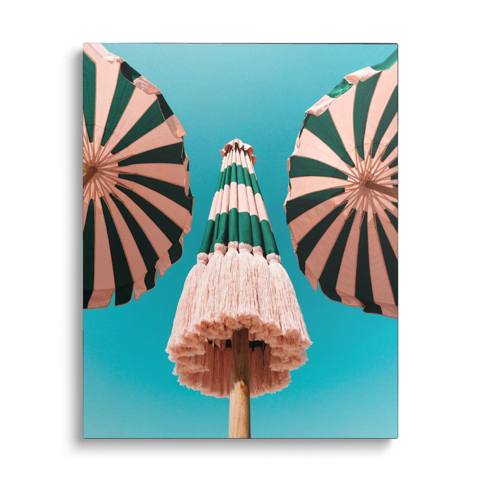 Toile Sous les Parasols vue de face sur fond blanc : photographie de parasols à rayures roses et vertes frangés, vus du dessous sur un ciel turquoise