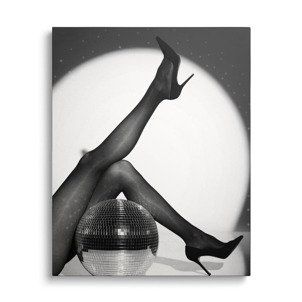 Toile Spotlight vue de face sur fond blanc : photographie noir et blanc de jambes en collants et escarpins dans un halo de projecteur, près d’une boule à facettes