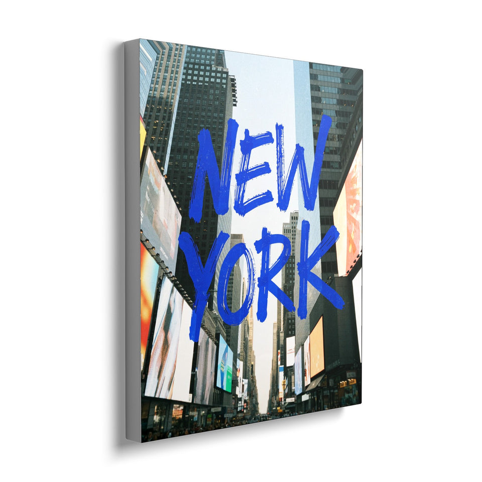 Toile Times Square 40 × 50 cm, vue de trois quarts avec tranche blanche : mots « New York » peints au pinceau bleu sur une photographie de gratte-ciel et d’écrans publicitaires