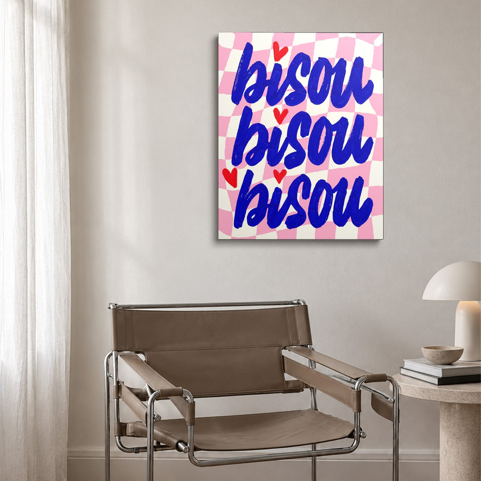 Toile Trois Bisous accrochée au-dessus d’un fauteuil en cuir et acier