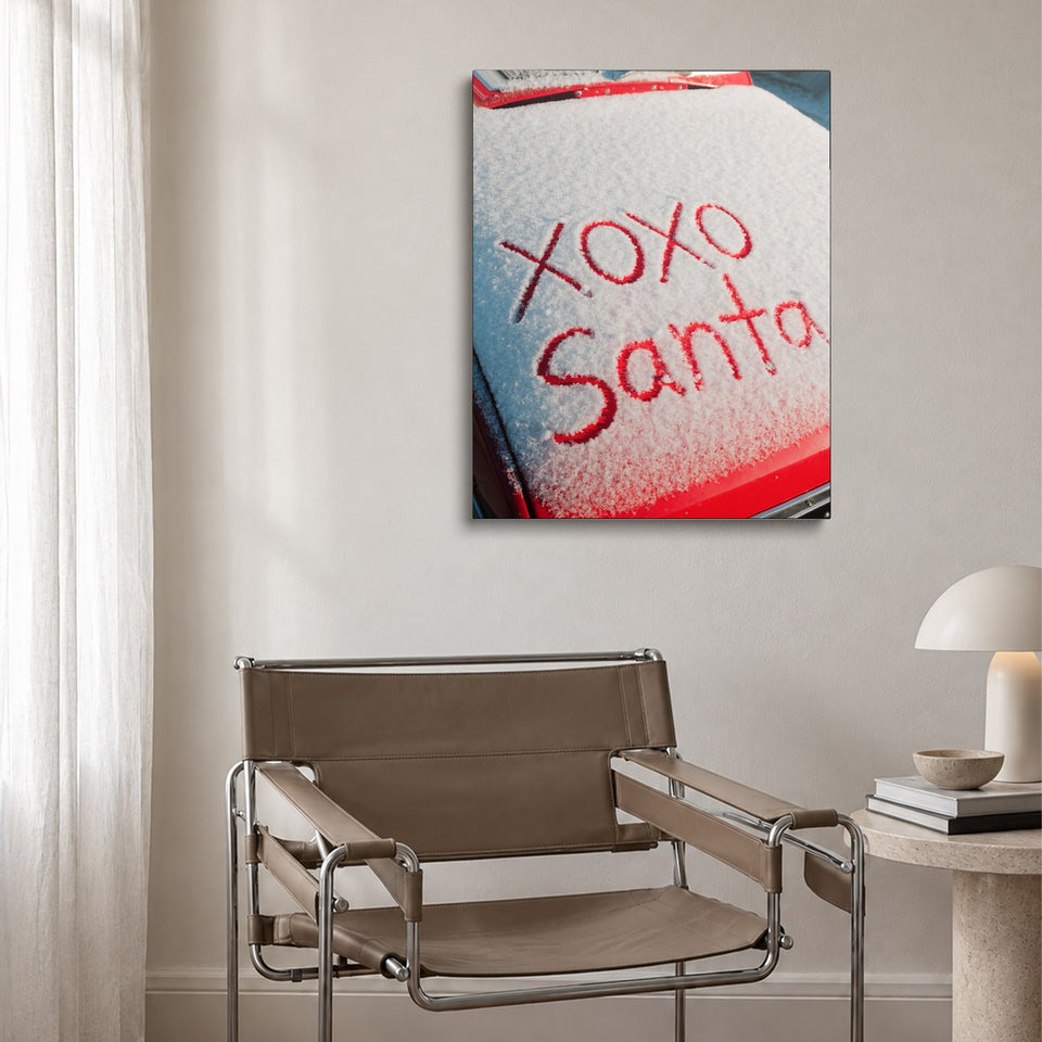 Toile XOXO Santa accrochée au-dessus d’un fauteuil en cuir et acier